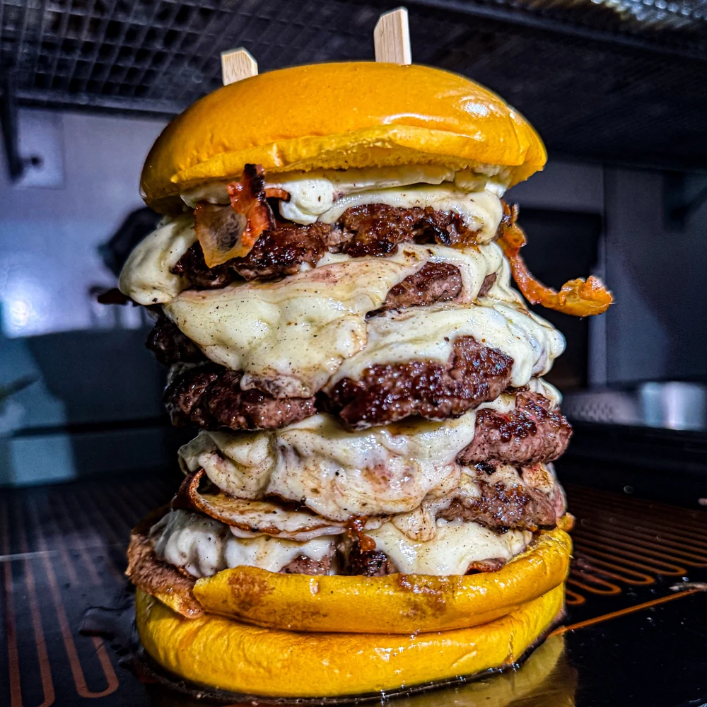 Hambúrguer alto com várias camadas de carne e queijo derretido